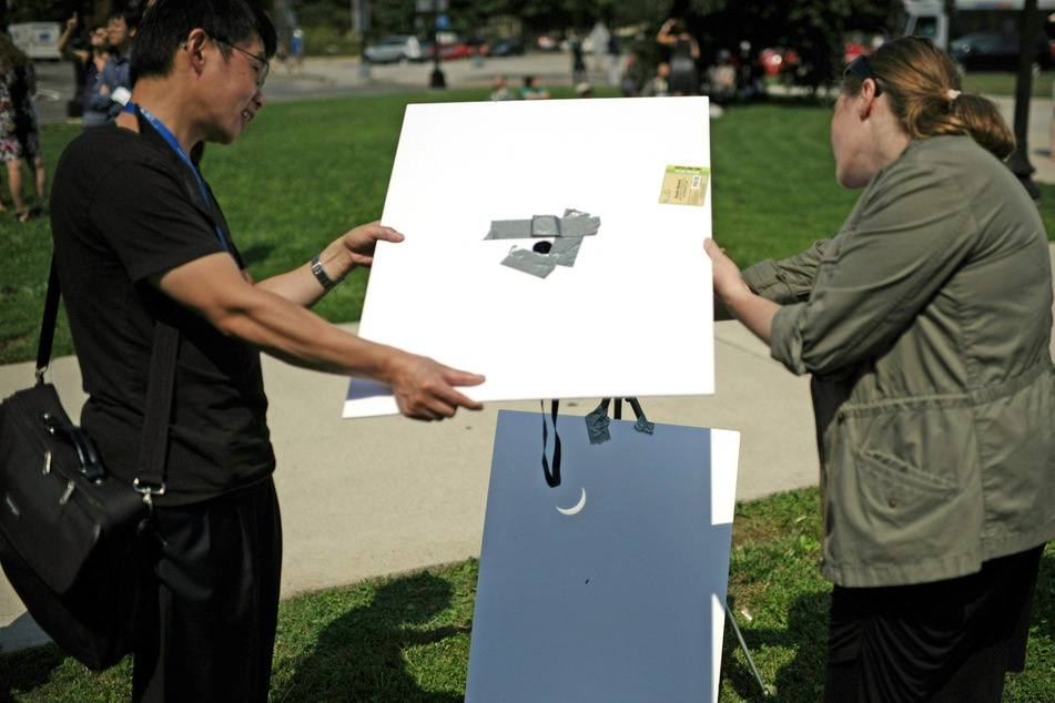 If you can't get any eclipse specs you can make a pinhole projector to see the spectacle. Eclipse viewers in 2017 in Washington, DC, catching a glimpse of the partial eclipse with a projector.