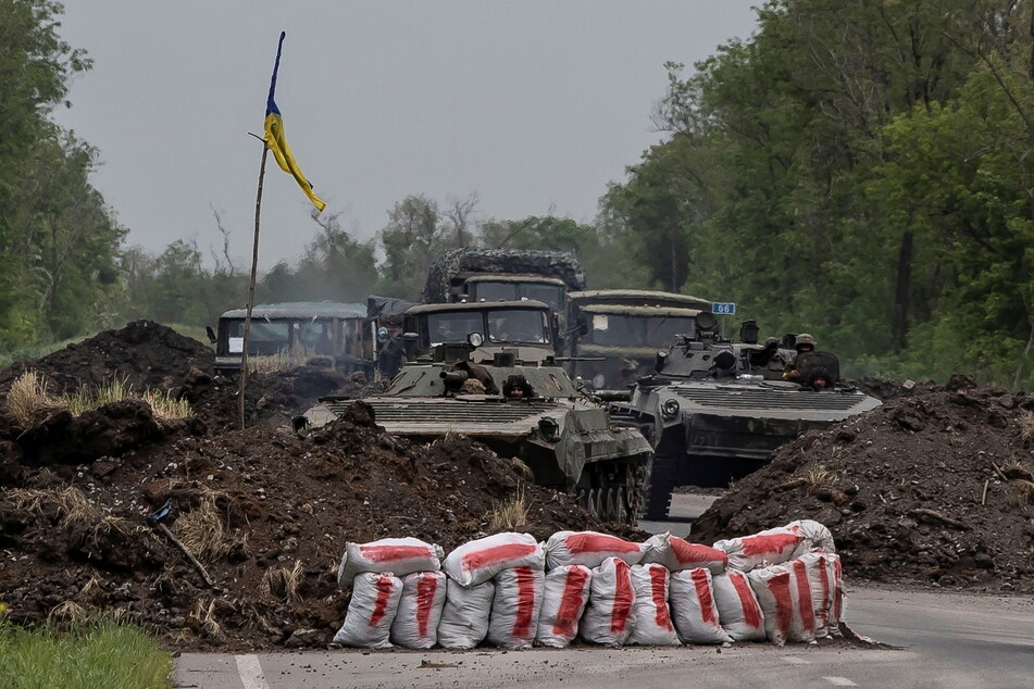 Ukrainian service members ride on top of a military vehicle in the Donetsk region amid Russia's invasion.
