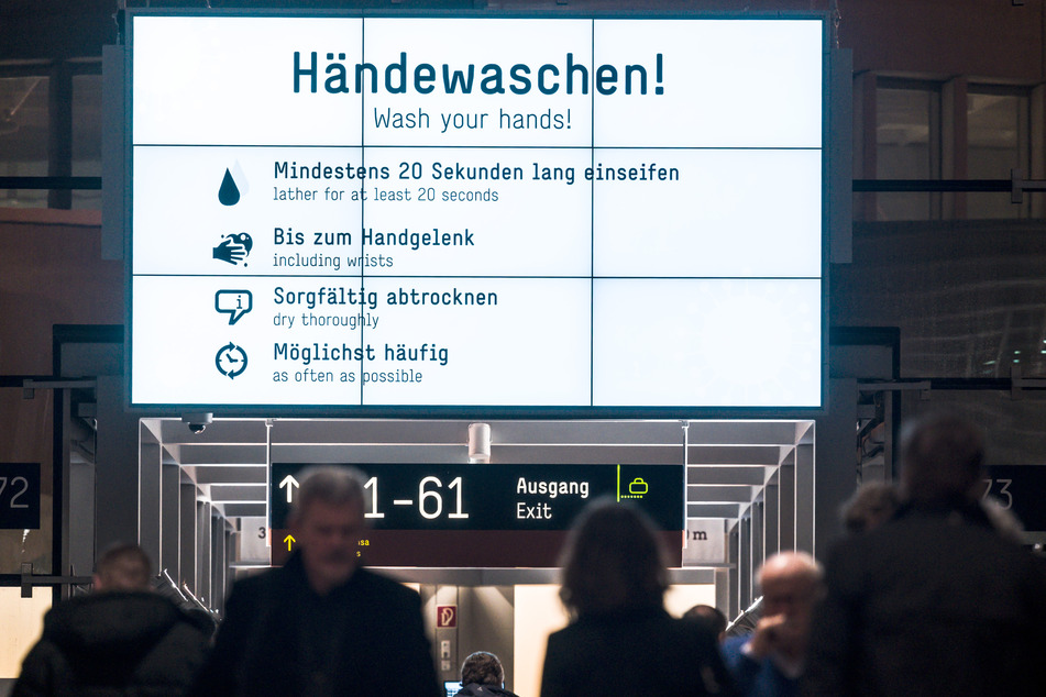 Im Abflugbereich des Flughafens Köln/Bonn sind auf Monitoren Tipps zum Schutz vor Infektionen in deutscher und englischer Sprache zu lesen.