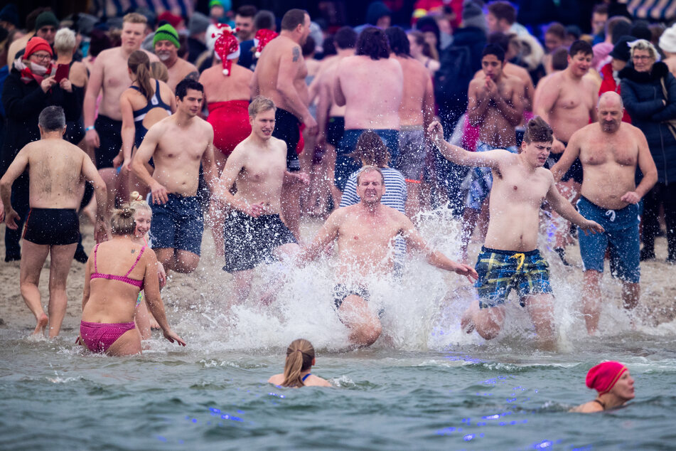 Schwimmer laufen beim traditionellen Anbaden am Neujahrstag ins Wasser.