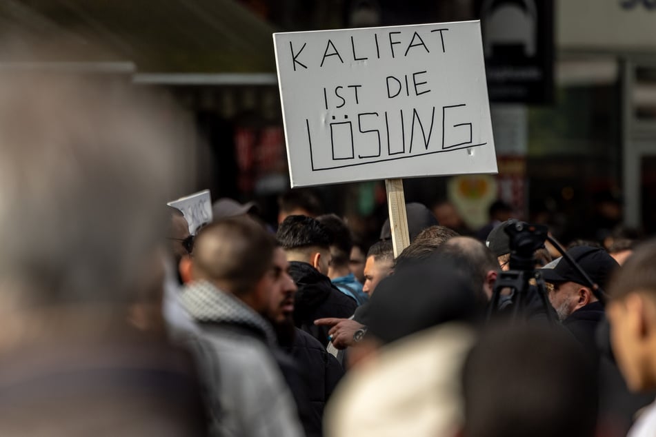 Teilnehmer einer Islamisten-Demo in Hamburg halten ein Plakat mit der Aufschrift "Kalifat ist die Lösung" in die Höhe.