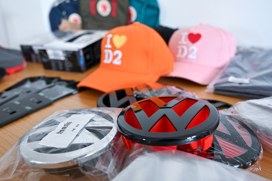 Nachgemachte Volkswagen-Logos und andere Fäschungen liegen im Zollamt am Flughafen Leipzig auf einem Tisch.