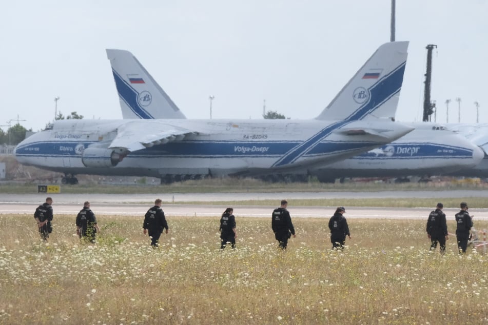 In unmittelbarer Nähe der russischen Antonov-Flieger, die in Leipzig festgesetzt sind, suchen Polizisten nach Drohnen-Teilen.