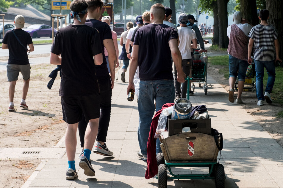 Mit einem Bollerwagen, einem Einkaufswagen und Bierflaschen in den Händen ziehen junge Leute am Vatertag durch Hannover.