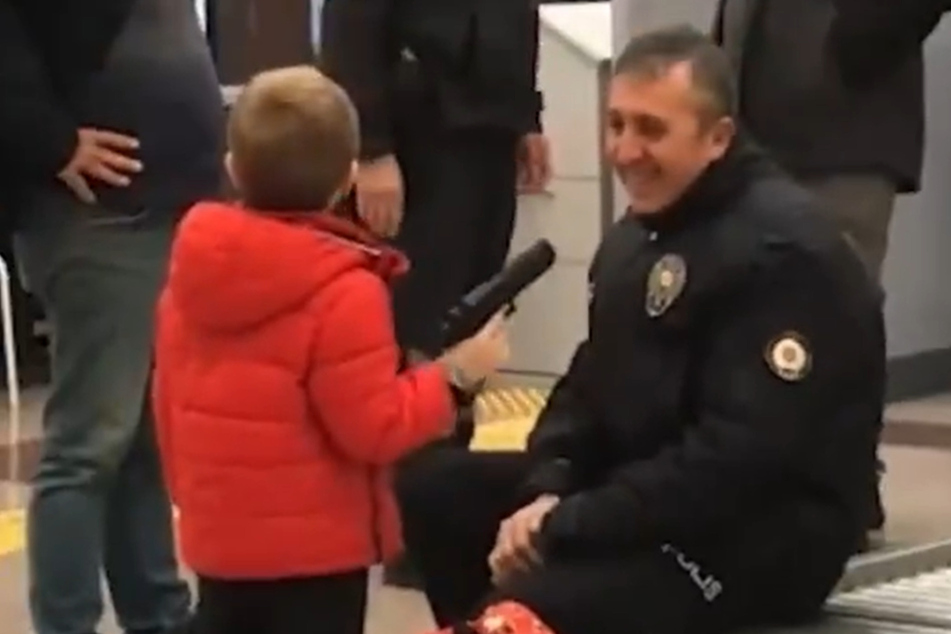 Stolz präsentiert der Junge (6) seine Spielzeugpistolen einem Polizisten.