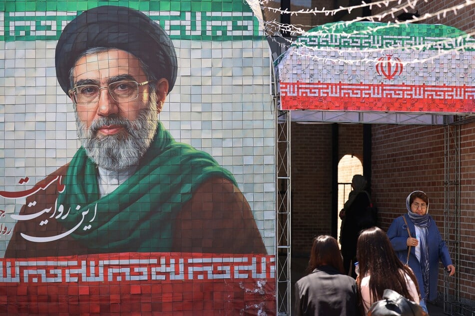 A commuter walks past a large tiled image of Iran's current leader, Ayatollah Mojtaba Khamenei, at the entrance to the metro in Tehran on May 9, 2026.