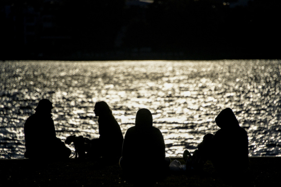 Menschen sitzen um Ufer der Außenalster in der Abendsonne.