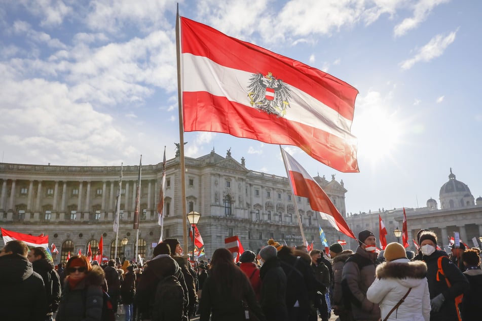 Österreich, Wien: Protestteilnehmer halten während einer Demonstration gegen die Corona-Maßnahmen der Regierung Fahnen hoch.