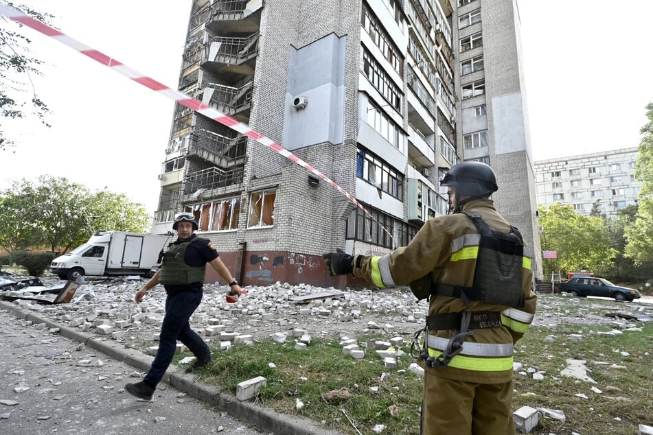 Rettungskräfte stehen vor einem durch russischen Beschuss beschädigten Wohnhochhaus in Saporischschja. (Archivbild)