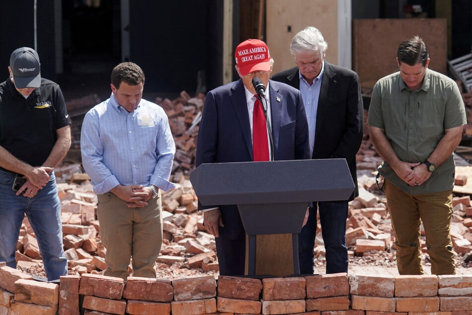 Trump (c.) has sought to make political capital out of the disaster, accusing the Biden administration, without evidence, of ignoring the crisis and denying help to his supporters.