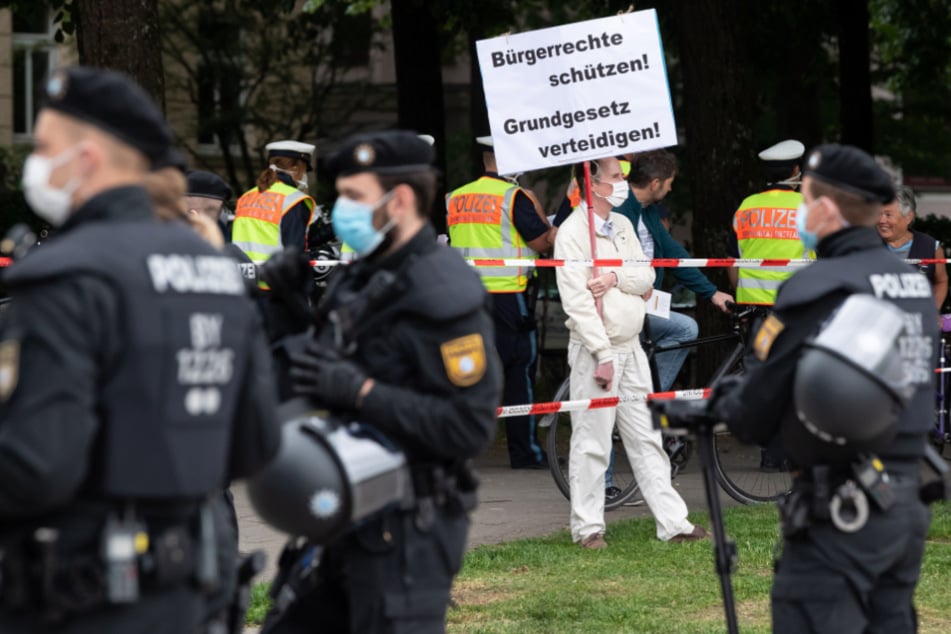 München: Ein Teilnehmer einer Demonstration gegen die Anti-Corona-Maßnahmen der Politik steht am Rand der Theresienwiese und hält ein Schild mit der Aufschrift "Bürgerrechte schützen! Grundgesetz verteidigen" in den Händen.