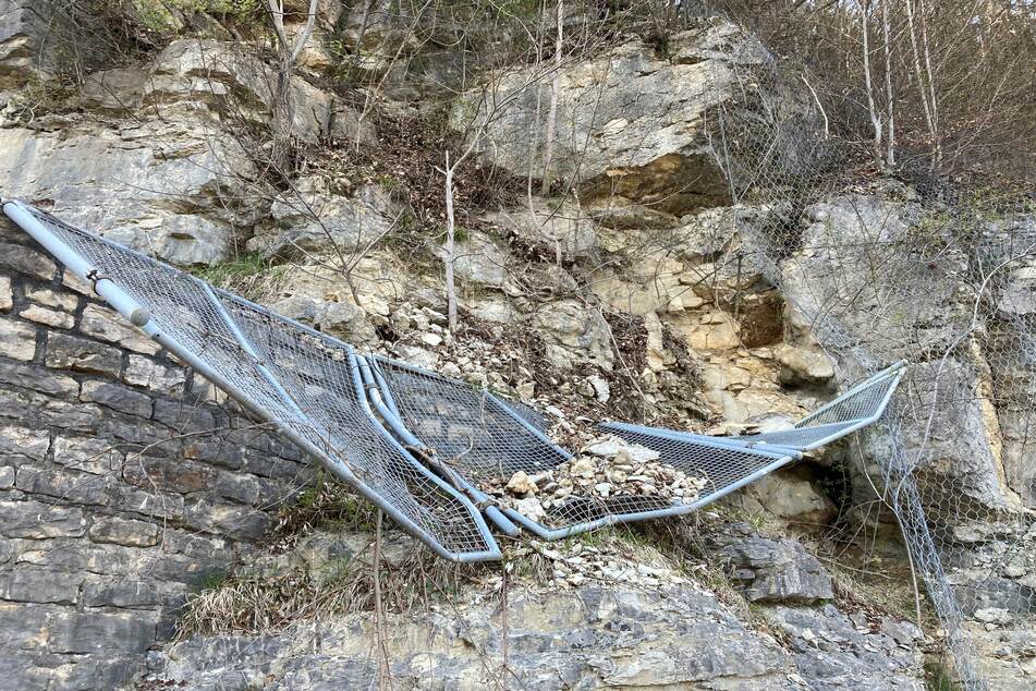 Ein durch kleinere Felsstürze beschädigtes Gitter hängt an einem Felsen über der A8, die für mehrere Tage gesperrt werden musste.