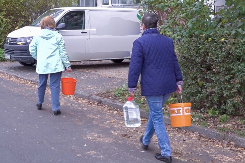 Anwohner schleppen vom Wasserwagen abgefülltes Wasser in ihre Wohnungen.