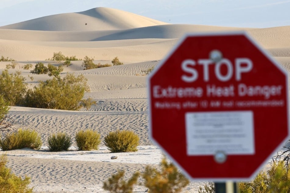 A "STOP Extreme Heat Danger" sign stands at Mesquite Flat Sand Dunes during a long-duration heat wave in Death Valley National Park, California, in summer 2024.