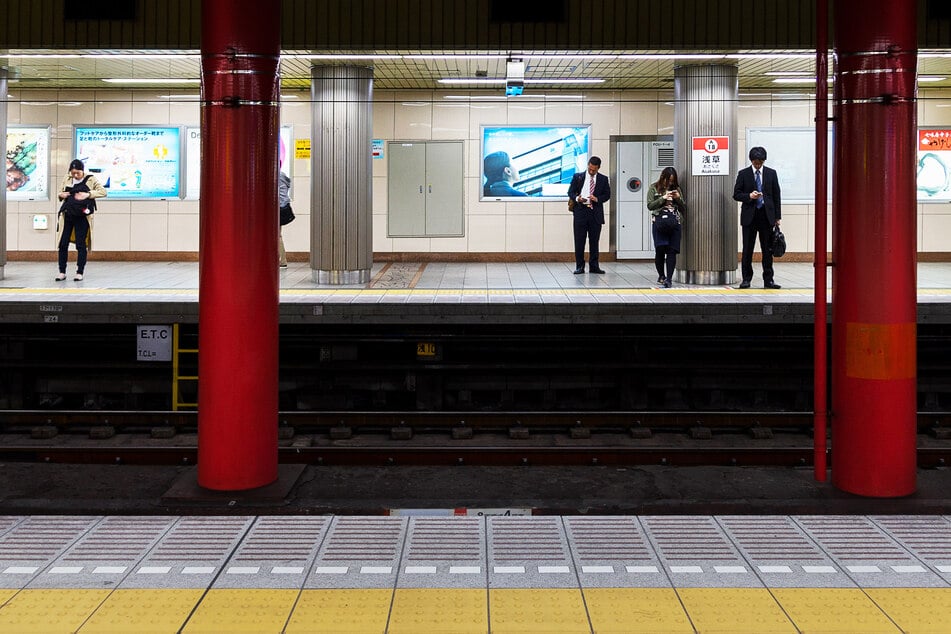 Etwa ein Meter Höhenunterschied gibt es an U-Bahnstationen in Tokio zwischen Bahnsteig und Gleisen. Züge rauschen vorbei.