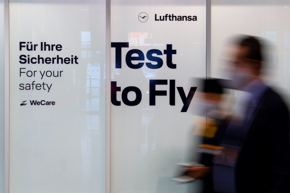 Mitarbeiter von Lufthansa laufen am Flughafen München in an einem Covid-19 Testcenter vorbei.