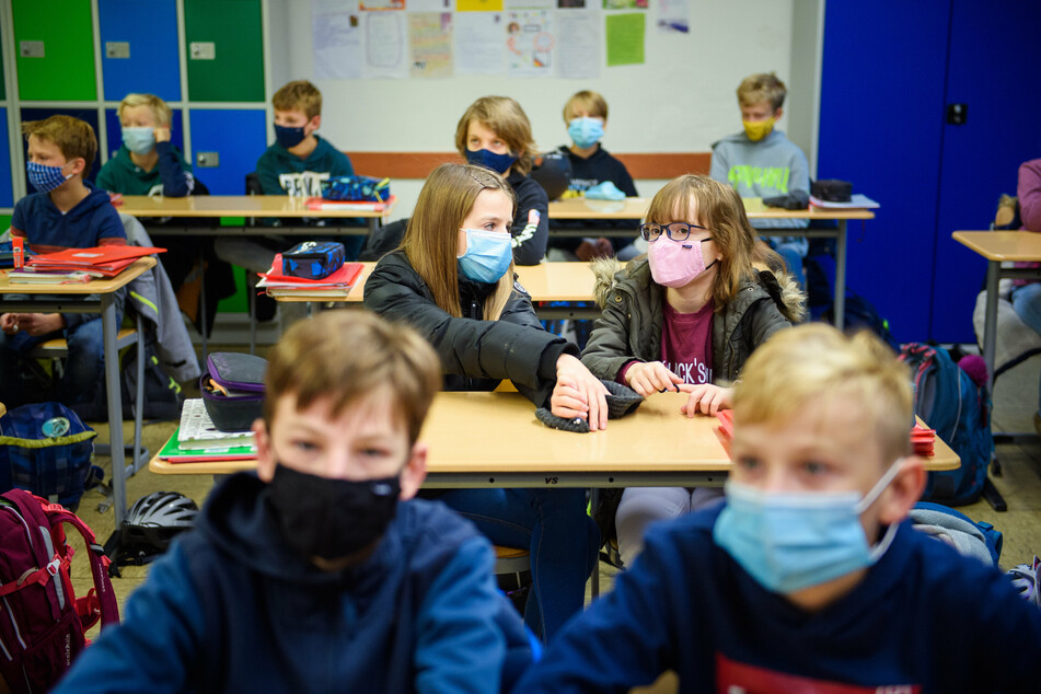 Schülerinnen und Schüler sitzen mit einer Maske im Unterricht.