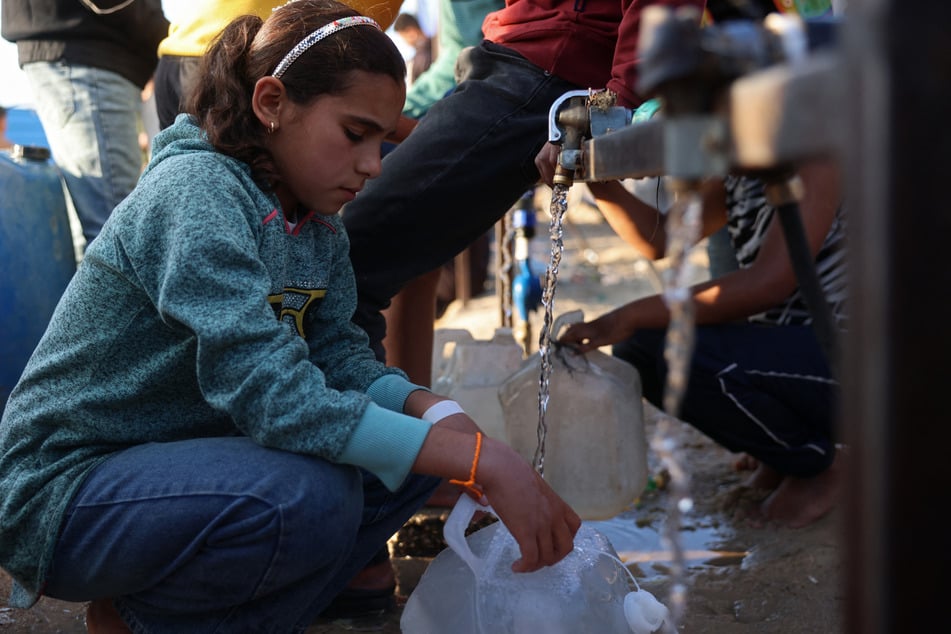 A girl fills a container with water at a makeshift camp for displaced Palestinians in Khan Younis, in the southern Gaza Strip, on April 10, 2026.