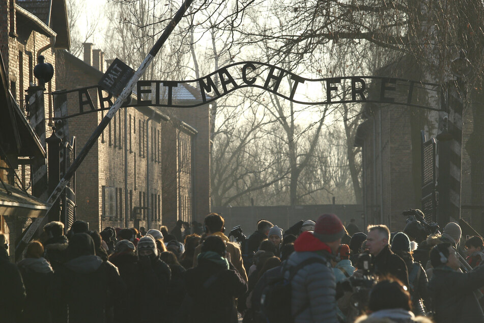 Auschwitz concentration camp: People stand in front of the main gate inscribed with the slogan "Arbeit macht frei" (Work makes you free). Soviet troops Auschwitz on 27 January 1945.