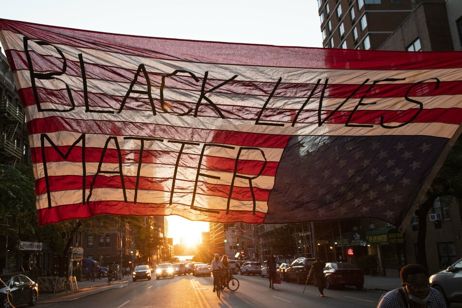 Die Sonne geht unter hinter einer über eine Straße gespannte, umgedrehten US-Flagge bei einer friedliche, aber lautstarke Demonstrationen Mitte Juni der "Black Lives Matter"-Bewegung.