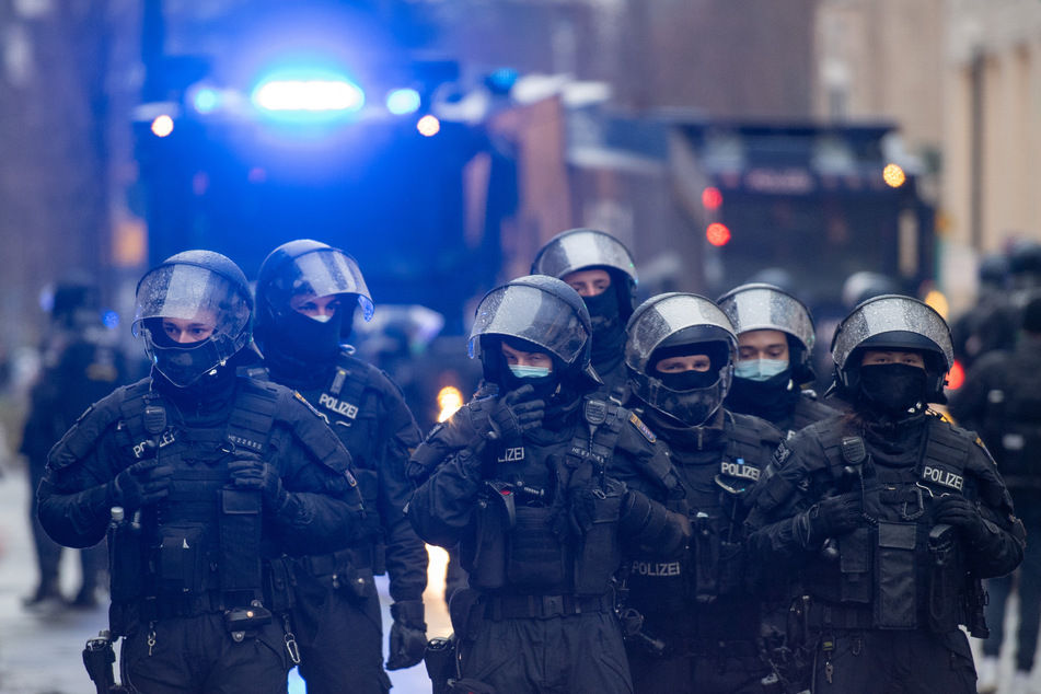 Polizisten sperren, während einer Demonstration gegen Corona-Regelungen, mit Wasserwerfern und Hundertschaften eine Straße ab.