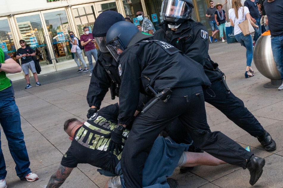 Polizisten halten bei einer Demonstration auf dem Alexanderplatz einen Mann fest.