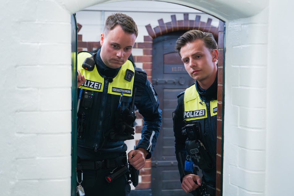 Polizeikommissar Valentin Otto (l.) und Polizeioberkommissar Pascal Will (27) schauen im Polizeigewahrsam in eine Zelle.