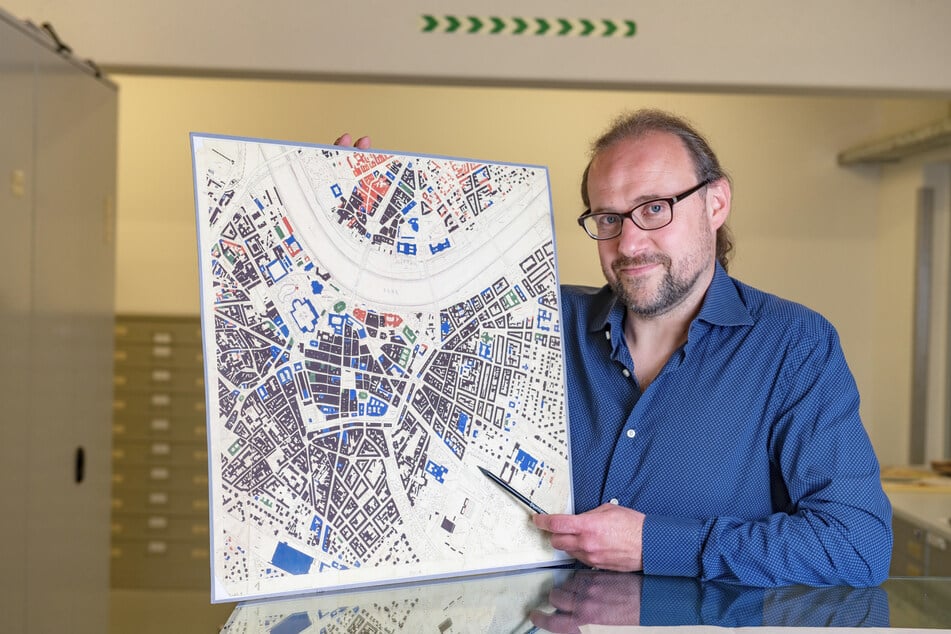 Archivar Patrick Maslowski (43) zeigt auf einer alten Schadenskarte, wo die Kohlebohrung stattfinden sollte. Schwarz eingezeichnete Bereiche waren nur noch Trümmer.