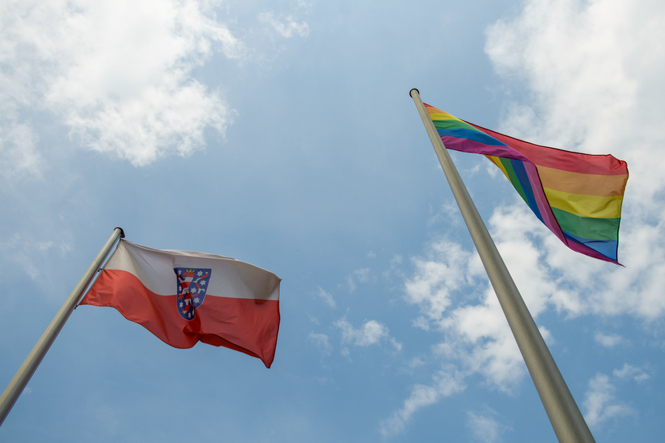 Die Thüringen-Fahne und die Regenbogenfahne wehen vor der Staatskanzlei in Erfurt. Mittlerweile können Transpersonen ihr Geschlecht unkompliziert ändern. Es gibt derzeit zahlreiche Anträge in Thüringen.