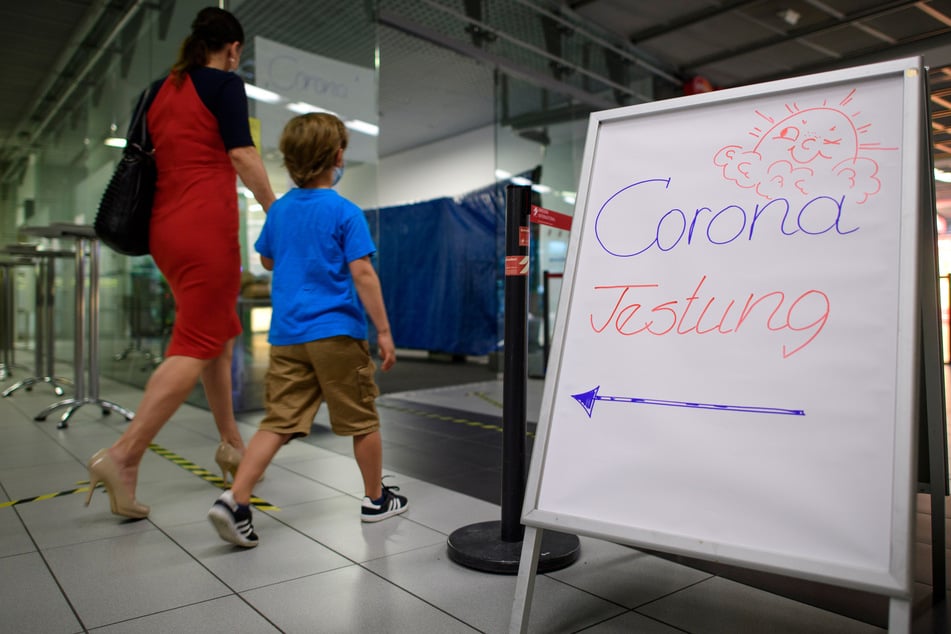 Eine Frau geht mit ihrem Sohn in die Corona-Teststation für Urlaubsrückkehrer am Flughafen Dresden International.