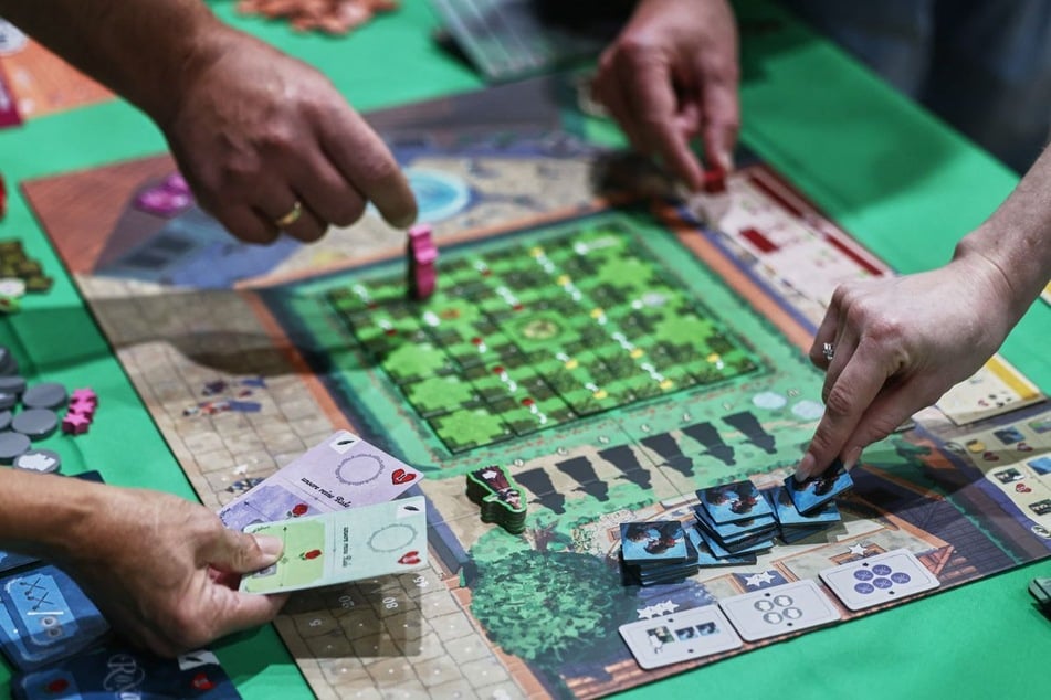 Besucher spielen auf der Publikumsmesse "Spiel Essen" das Brettspiel "Roxane".