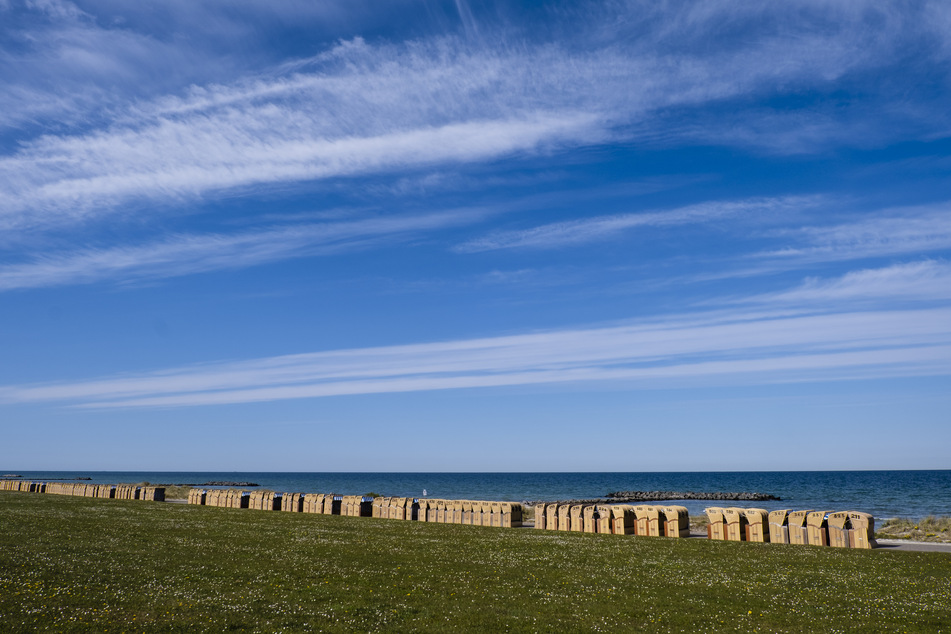 Verschlossene Strandkörbe stehen hintereinander aufgereiht an der Promenade am Schönberger Strand.