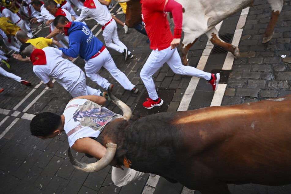 Teilnehmer rennen beim Stierlauf durch die Altstadt von Pamplona vor den Bullen her. (Archivbild)