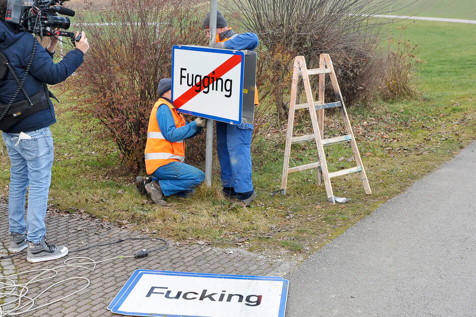 Arbeiter bringen das neue Ortsschild von Fugging an.
