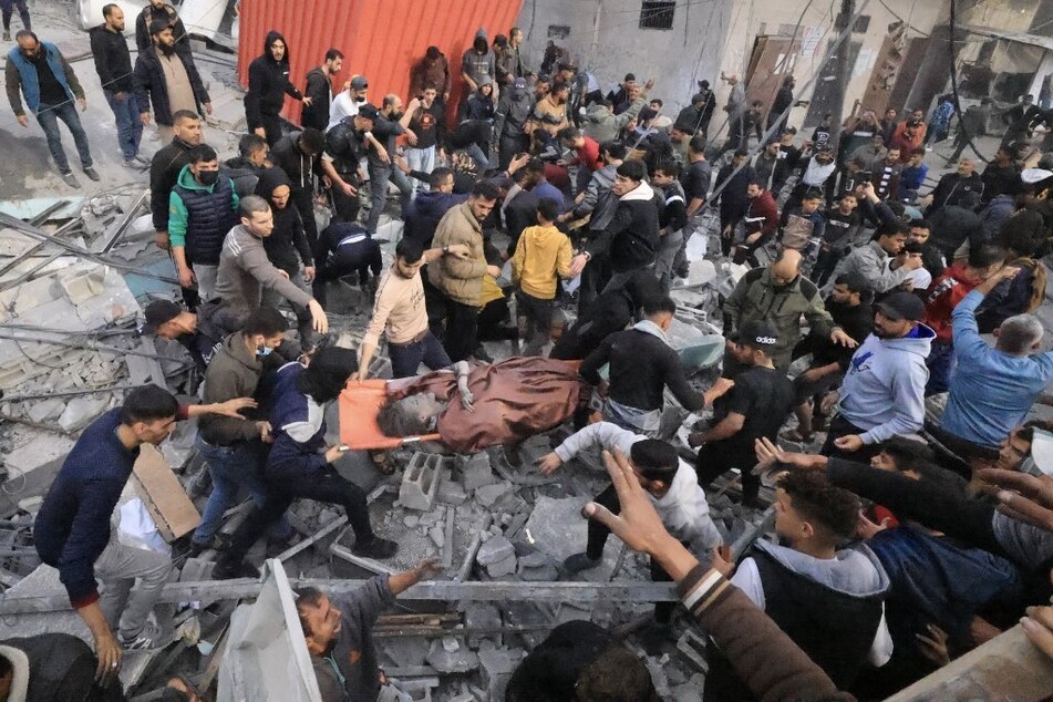 People evacuate a wounded girl following an Israeli strike on the Ali ben Abi Taleb Mosque in Rafah in the southern Gaza Strip on December 20, 2023.