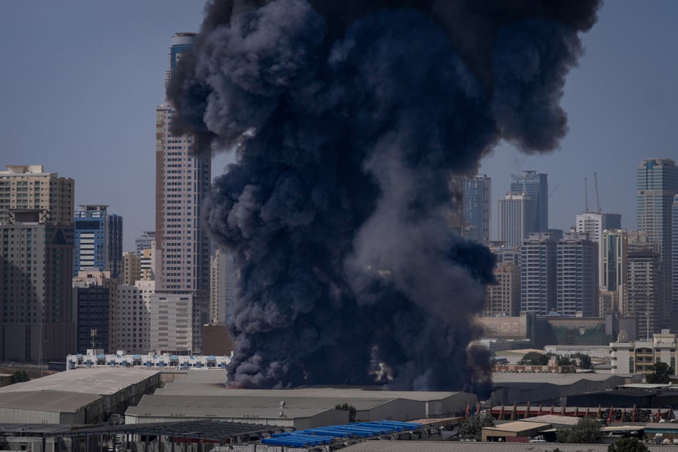 Eine schwarze Rauchwolke steigt aus einem Lagerhaus im Industriegebiet von Sharjah City in den Vereinigten Arabischen Emiraten auf.