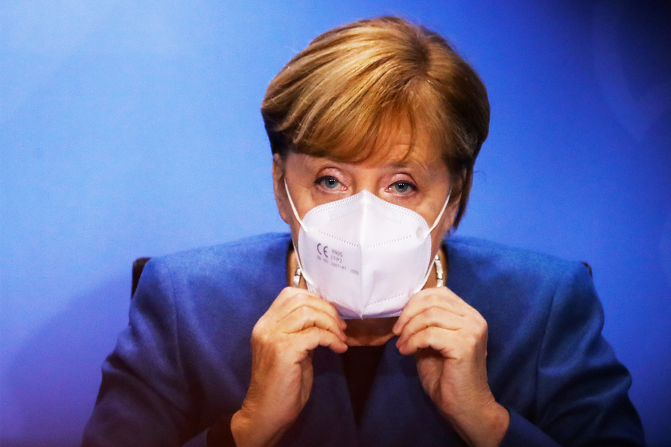 Bundeskanzlerin Angela Merkel (66) setzt ihre Gesichtsmaske auf am Ende einer Pressekonferenz im Kanzleramt nach einem Treffen mit den Ministerpräsidenten der Länder zum weiteren Vorgehen in der Corona-Pandemie.