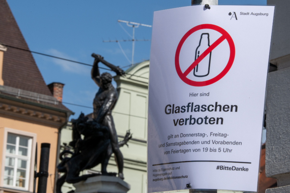 Ein Schild weist am Herkulesbrunnen in der Maximilianstraße in Augsburg auf das zeitweilige Verbot von Glasflaschen hin. Die Stadt reagierte damit auf die Party-Exzesse in der Innenstadt.
