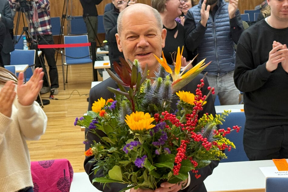 Bundeskanzler Olaf Scholz (66) freut sich auf der Parteikonferenz über seinen Blumenstrauß.