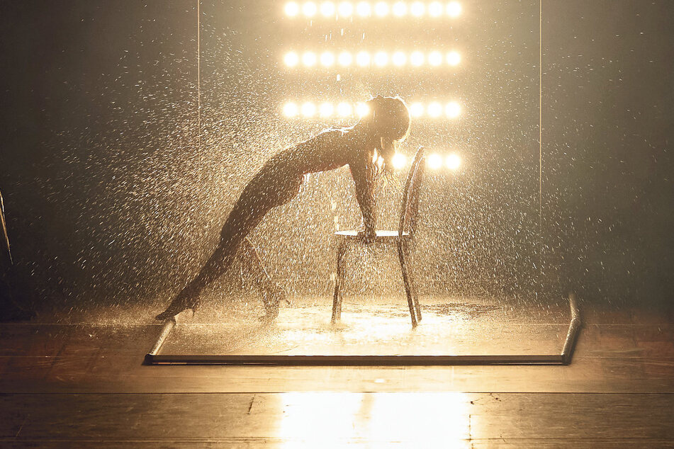 Die ikonische Filmszene in der Musical-Variante: Alex wird auf einem Stuhl tanzend von Wasser begossen.
