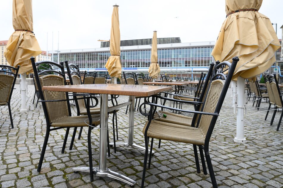 Leere Tische und Stühle stehen vor einem geschlossenen Restaurant auf dem Altmarkt vor dem Kulturpalast.