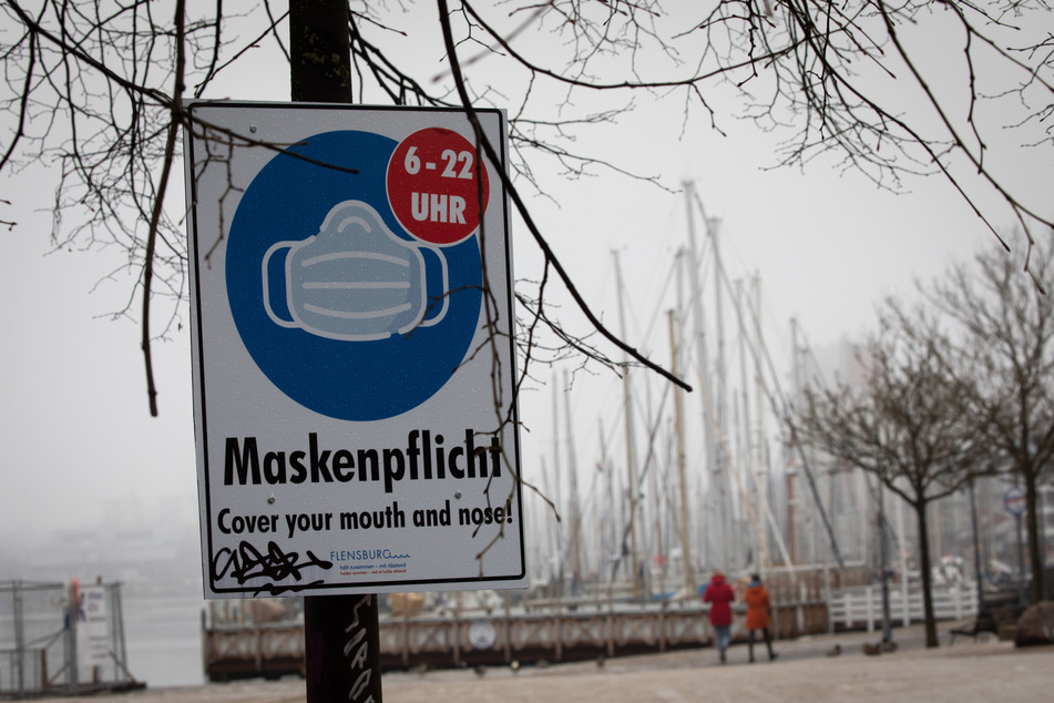 Ein Hinweisschild zur Maskenpflicht ist an der Hafenspitze in der Flensburger Innenstadt zu sehen.