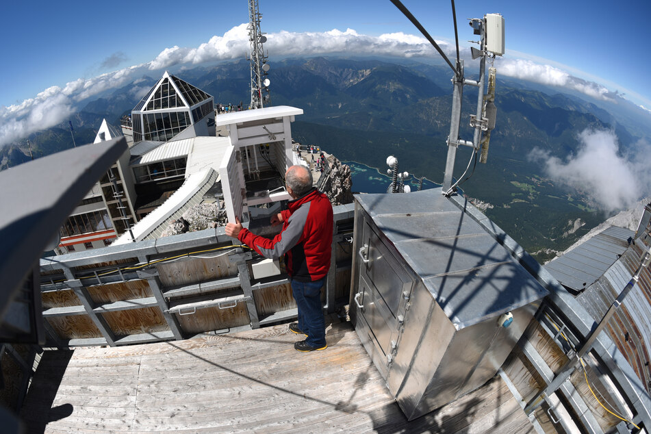 Ein DWD-Mitarbeiter steht auf der Zugspitze am Dach der Wetterwarte.