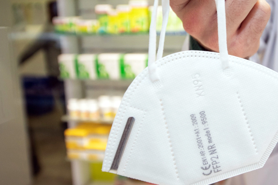 Ein Apotheker hält eine FFP2-Maske: Die Maskenpflicht in den Bundesländern soll verschärft werden.