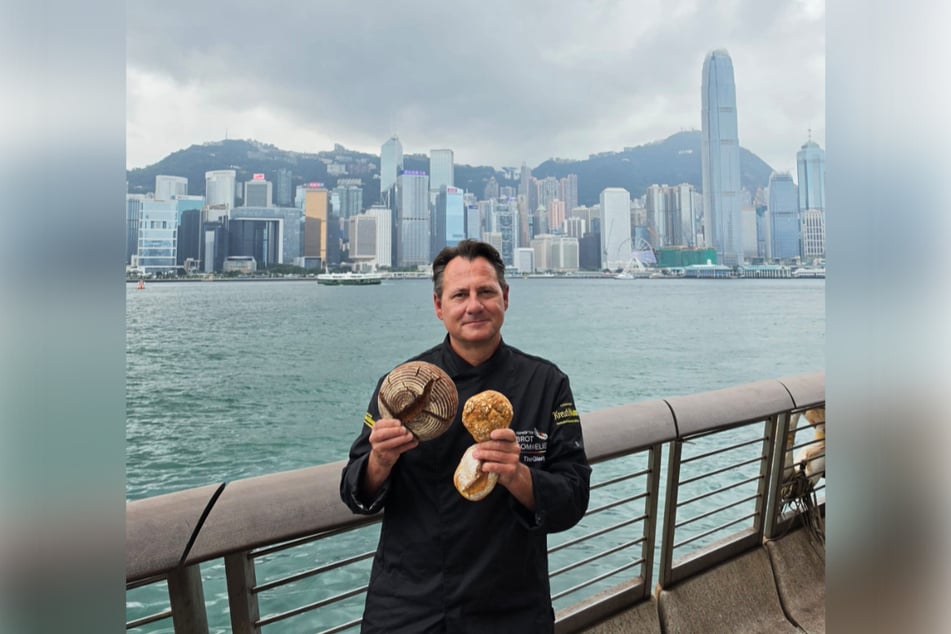 Fertig: Tino Gierig (56) zeigt Brot und Brötchen vor der Skyline von Hongkong.