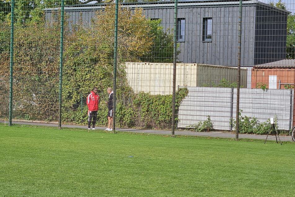 Anderson Lucoqui (29, l.) tauscht sich mit René Deffke (59) am Zaun des Cottbuser Trainingsplatzes aus.