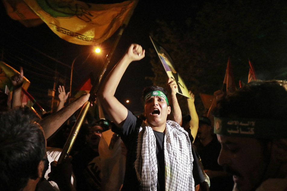 Iraqis shout slogans during a demonstration near the suspension bridge leading to Baghdad's Green Zone and the US Embassy in Baghdad on October 18, 2023, protesting a strike on a Gaza hospital which killed hundreds a day earlier.