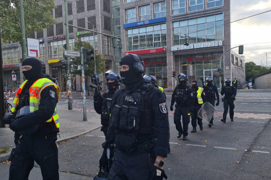 Einsatzkräfte der Polizei gehen am Elcknerplatz am Bahnhof Köpenick Berlin entlang.