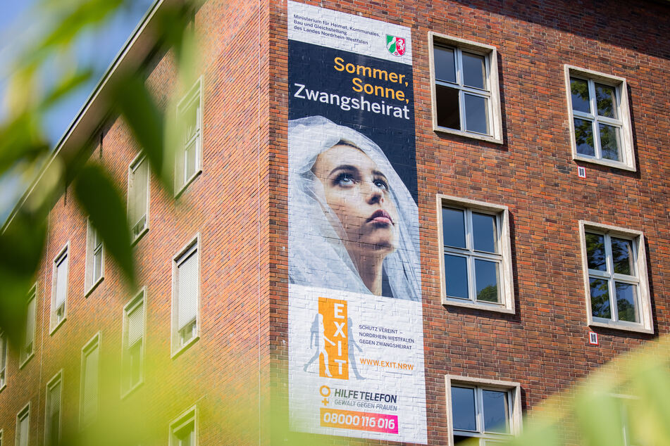 Ein Plakat mit der Aufschrift "Sommer, Sonne, Zwangsheirat" hängt am Ministerium für Heimat, Kommunales, Bau und Gleichstellung des Landes Nordrhein-Westfalen. Am Dienstag startete eine Kampagne.