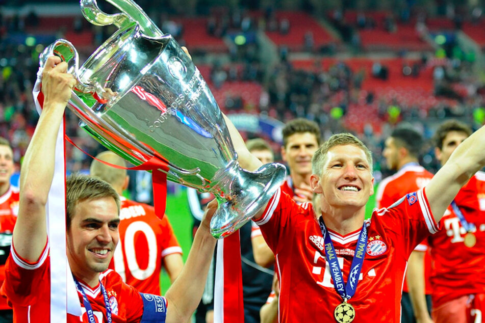 Philipp Lahm (36, l.) und Bastian Schweinsteiger (36, r.) von Bayern München feiern mit dem Pokal nach dem UEFA Champions League-Finale 2013 zwischen Borussia Dortmund und FC Bayern München im Wembley Stadion.